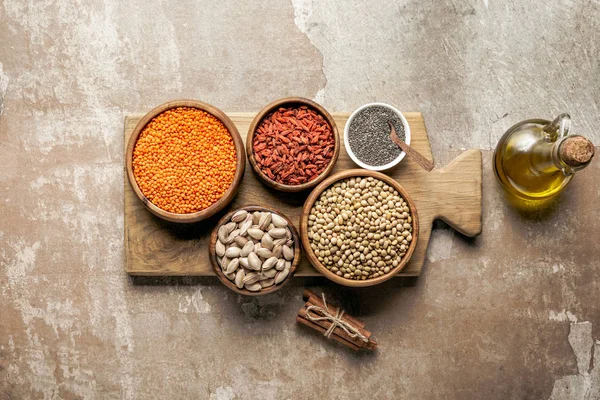 Top view of legumes, goji berries and chia seeds on wooden board with rustic background — Stock Photo