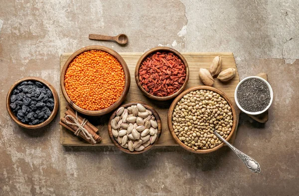 Draufsicht auf Holzbretter mit Hülsenfrüchten, Goji-Beeren und gesunden Zutaten mit rustikalem Hintergrund — Stockfoto