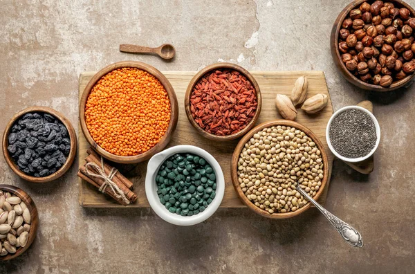 Top view of wooden board with legumes, goji berries and healthy ingredients with rustic background — Stock Photo