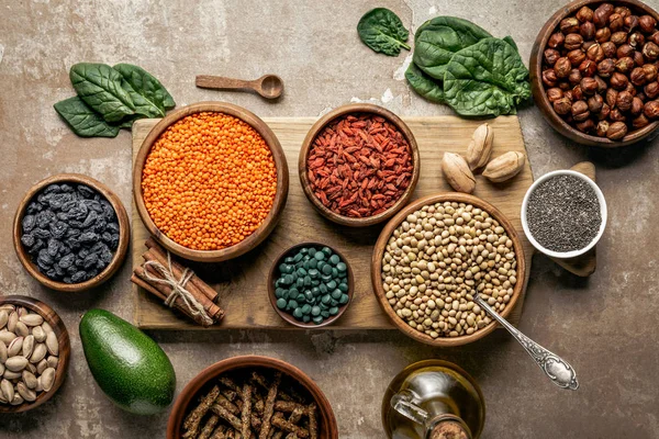 Top view of wooden board with legumes, goji berries and healthy ingredients with rustic background — Stock Photo