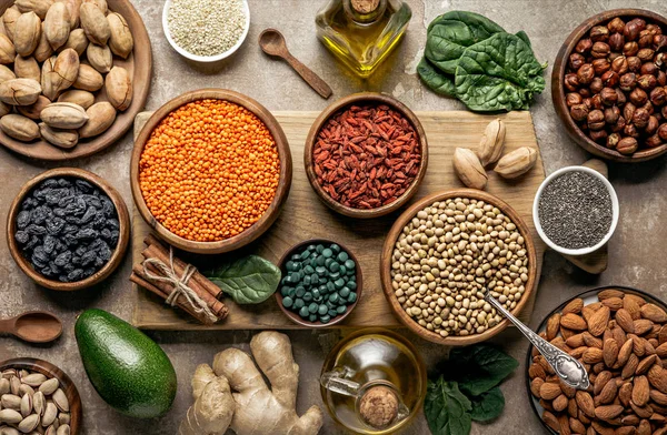 Tendido plano de tablero de madera con legumbres, bayas de goji e ingredientes saludables en la mesa — Stock Photo