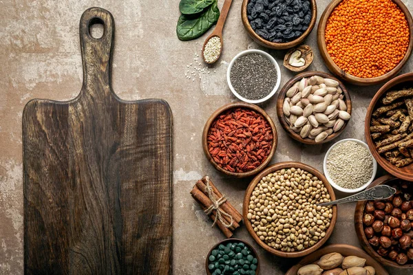 Draufsicht auf Holzbrett, Superfoods, Hülsenfrüchte und gesunde Zutaten auf rustikalem Hintergrund — Stockfoto