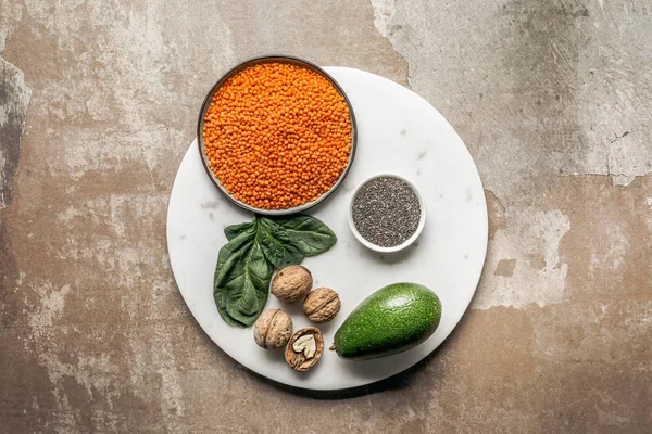 Graines de chia, avocat, lentilles rouges et noix sur plaque avec fond rustique texturé — Photo de stock