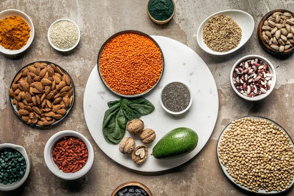 Flat lay of superfoods, legumes, nuts and avocado on textured rustic background — Stock Photo