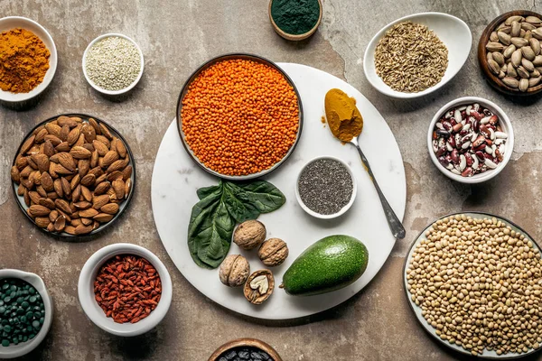 Flat lay of superfoods, legumes, nuts and avocado on textured rustic background — Stock Photo