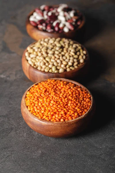 Selective focus of lentils, soy and beans in wooden bowls on table — Stock Photo