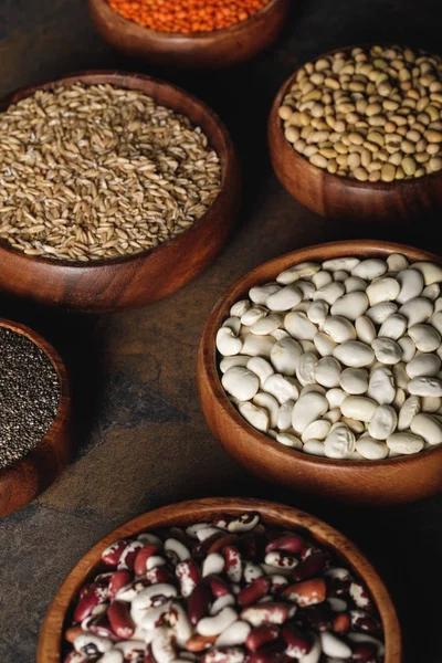 Variety of beans with oat groats in wooden bowls on table — Stock Photo