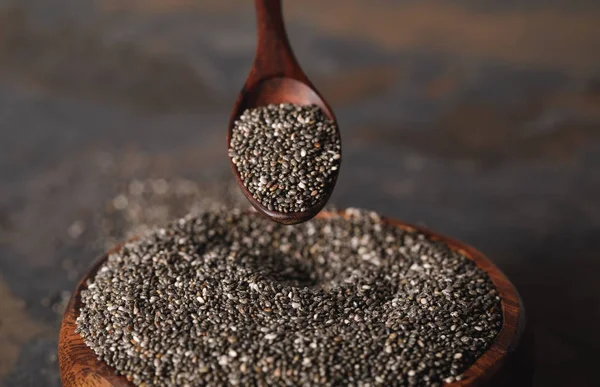 Foco seletivo de colher de madeira e sementes de chia na tigela — Fotografia de Stock