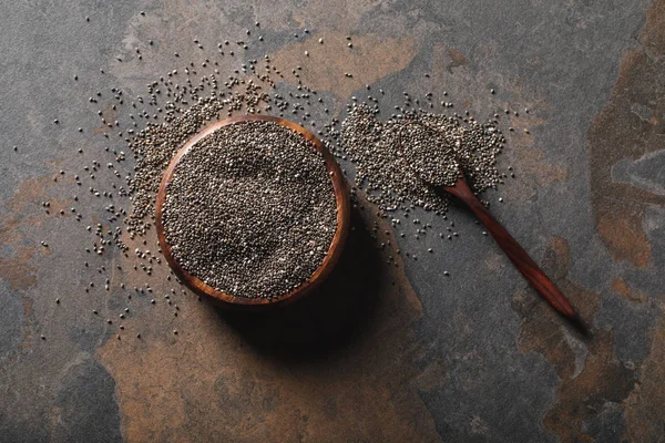 Vue du dessus du bol en bois plein de graines de chia avec cuillère sur la table — Photo de stock