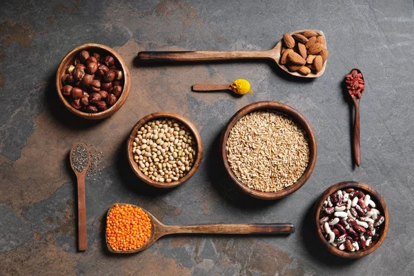 Vista superior de tigelas de madeira e colheres com superalimentos, legumes e grãos na mesa — Fotografia de Stock