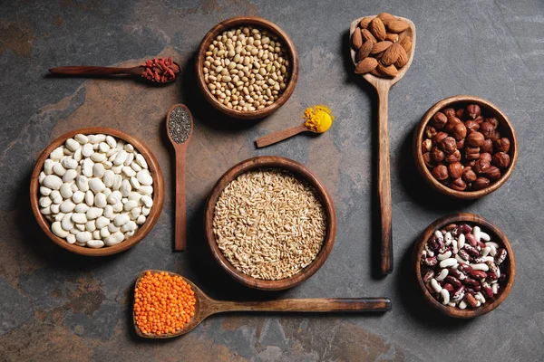 Colocação plana de tigelas de madeira e colheres com superalimentos, legumes e grãos na mesa — Fotografia de Stock