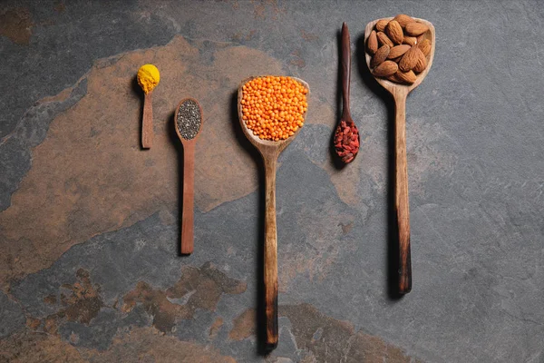 Top view of arranged wooden spoons with superfoods, red lentils and turmeric on table — Stock Photo