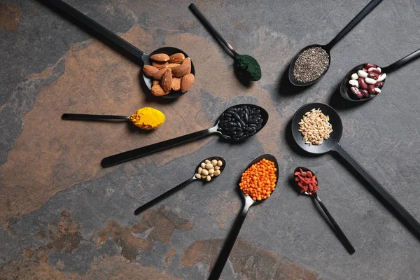 Flat lay of spoons with superfoods, legumes and grains on table — Stock Photo