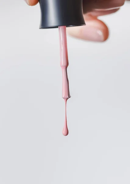 Частковий вид жінки, що тримає щітку з рожевим лаком для нігтів ізольовано на сірому — Stock Photo