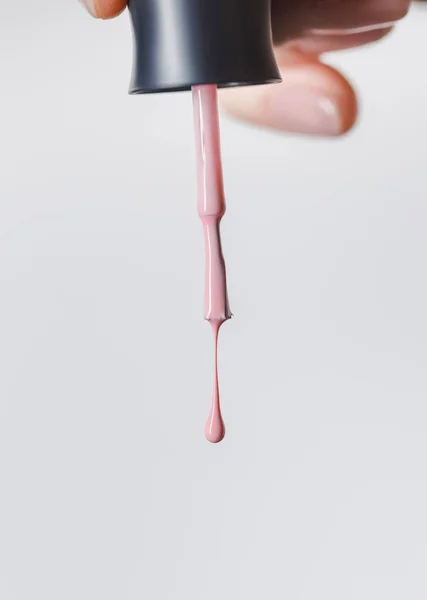 Partial view of woman holding brush with pink nail polish isolated on grey — Stock Photo