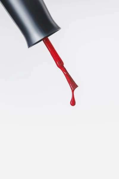 Pinceau vernis à ongles avec goutte rouge isolé sur gris — Photo de stock