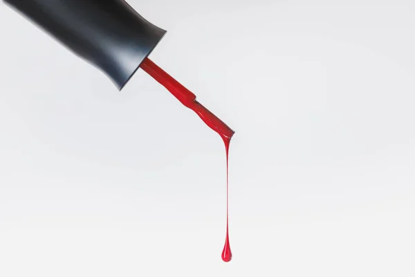 Close up view of nail polish brush with bright red lacquer drop isolated on grey — Stock Photo