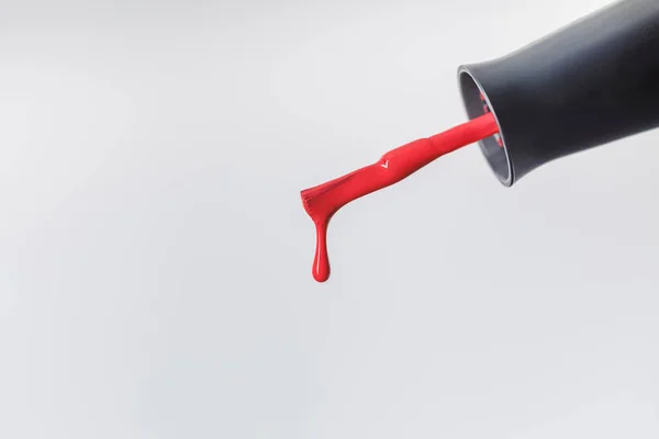 Nahaufnahme des Nagellackpinsels mit rotem Lacktropfen isoliert auf grau — Stockfoto
