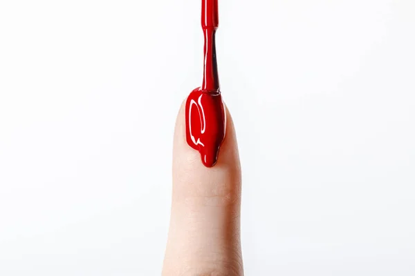 Vista recortada de la mujer aplicando esmalte de uñas rojo goteo en la uña aislada en gris - foto de stock