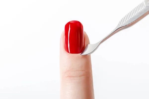 Bright red nail polish on fingernail with cuticle pusher isolated on white — Stock Photo