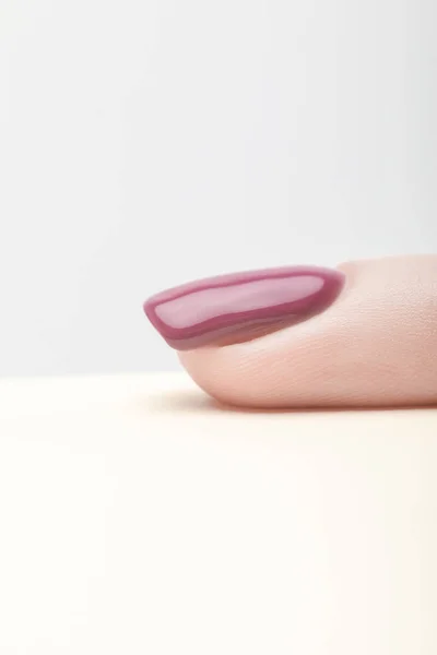 Fingernail with shiny purple nail polish on grey background — Stock Photo