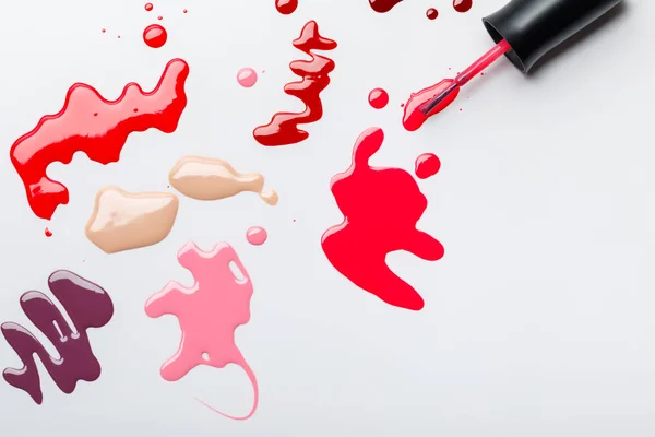 Top view of wet brush near colorful spills of nail polish isolated on grey — Stock Photo