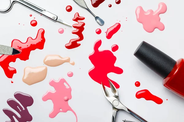 Top view of manicure set near multicolored spills of nail polish isolated on grey — Stock Photo