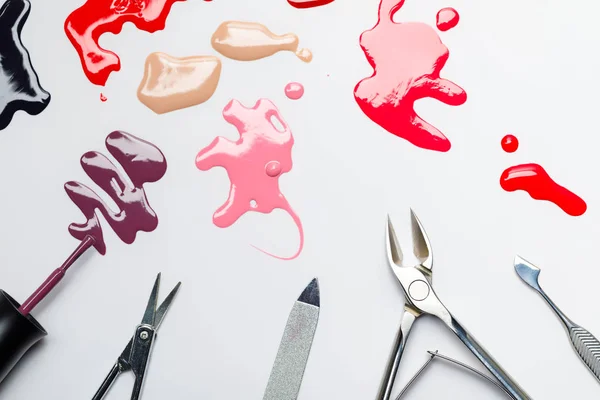 Top view spilled nail polish near manicure set isolated on grey — Stock Photo