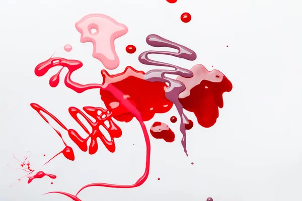 Top view of abstract spilled red and pink drops of nail polish isolated on grey — Stock Photo