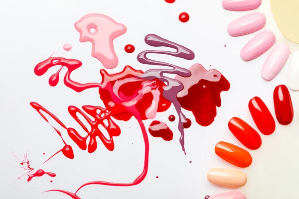 Top view of wet abstract multicolored spills near samples of nail polish isolated on grey — Stock Photo