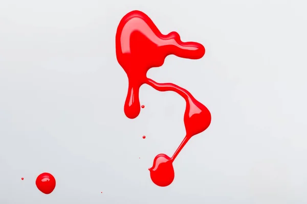 Вид зверху розлитий яскраво-червоний лак для нігтів ізольований на сірому — стокове фото