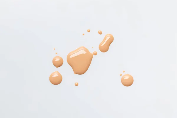 Top view of wet and shiny caramel drops of nail polish isolated on grey — Stock Photo