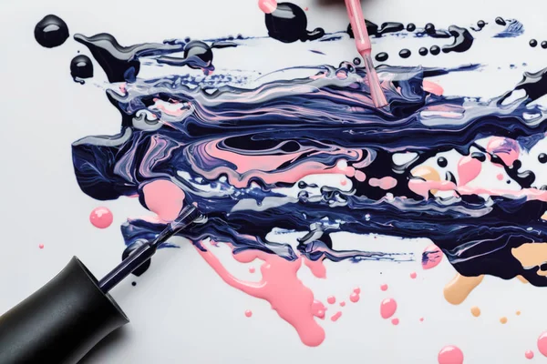 Top view of multicolored spill of nail polish with wet brushes isolated on grey — Stock Photo