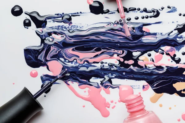 Top view of abstract multicolored spill of nail polish with wet brushes isolated on grey — Stock Photo