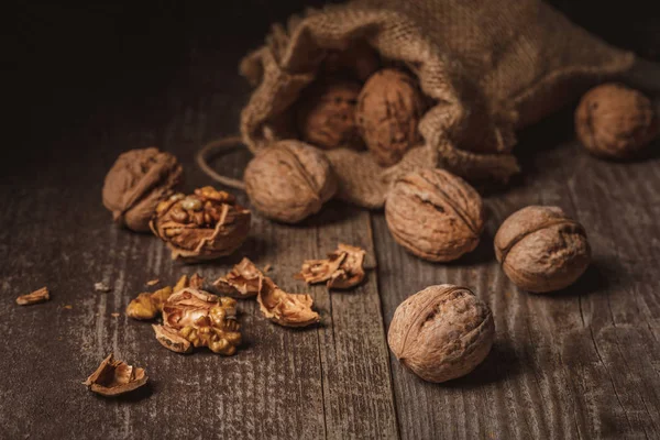 Close up view of walnuts in sack on wooden background — Stock Photo