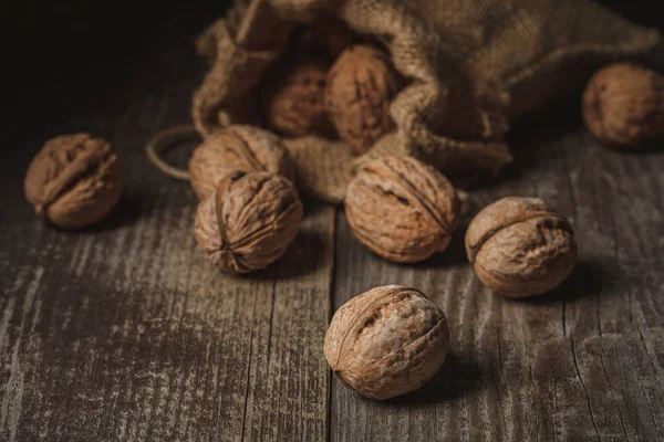 Close up view of walnuts in sack on wooden background — Stock Photo