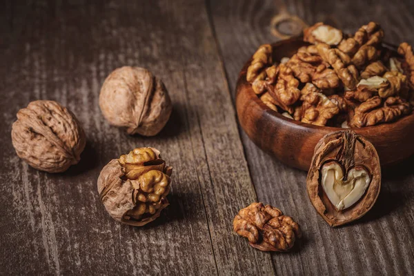 Close up view of walnuts in bowl on wooden surface — Stock Photo