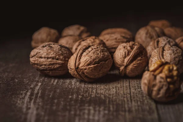 Close up view of walnuts on wooden tabletop on black backdrop — Stock Photo