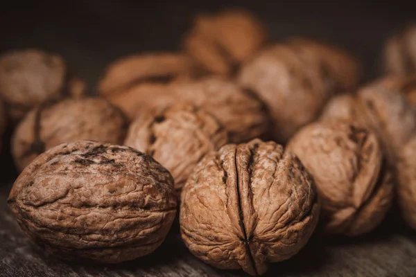 Close up view of walnuts on wooden tabletop on black backdrop — Stock Photo