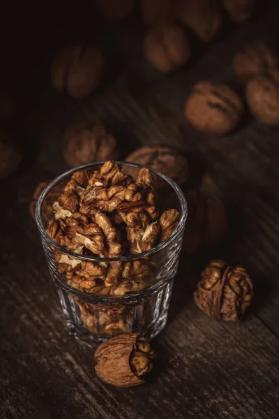 Close up view of shelled walnuts in glass on wooden surface — Stock Photo