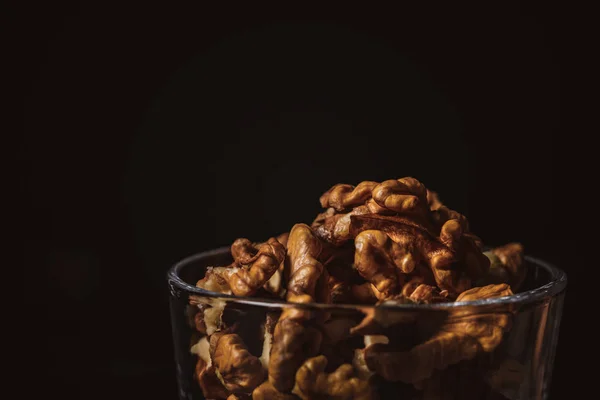 Close up view of shelled walnuts in glass on black background — Stock Photo