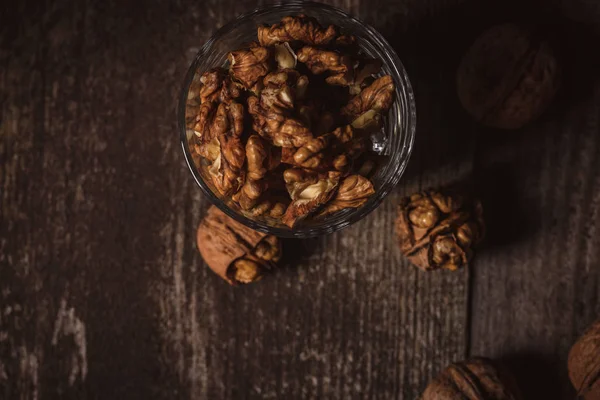 Верхний вид оболочки грецких орехов в стекле на деревянном фоне — стоковое фото