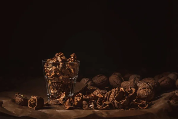 Close up view of shelled walnuts in glass on black backdrop — Stock Photo