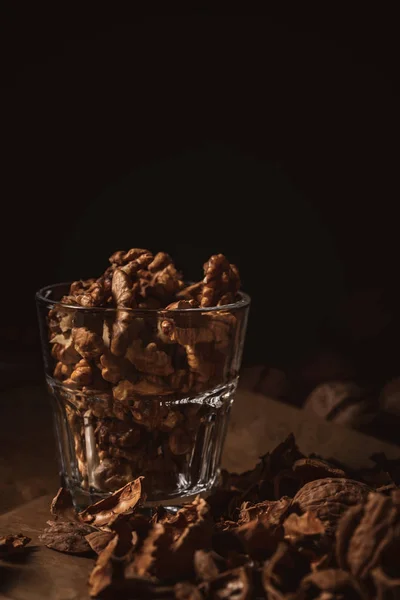 Close up view of shelled walnuts in glass on black backdrop — Stock Photo