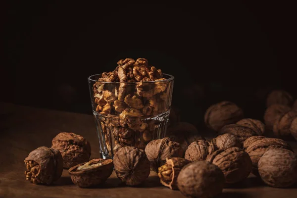 Close up view of shelled walnuts in glass on black backdrop — Stock Photo