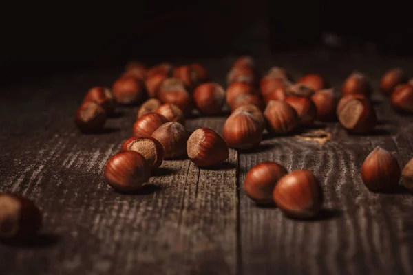 Close up view of hazelnuts on wooden surface on black background — Stock Photo