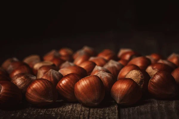 Close up view of hazelnuts on wooden surface on black background — Stock Photo