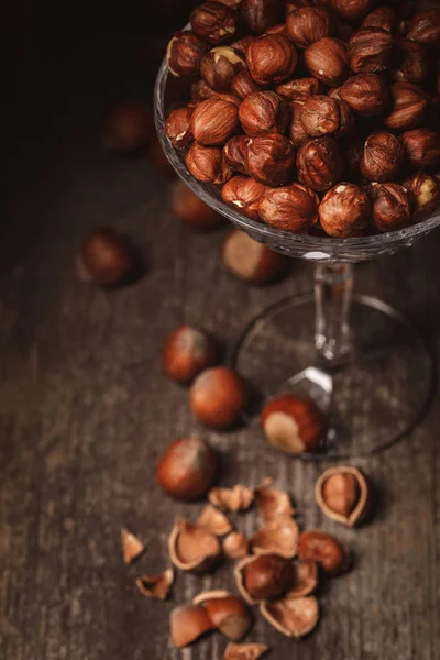 Close up view of shelled hazelnuts in glassware on wooden surface — Stock Photo