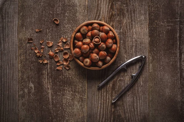 Vue du dessus des noisettes dans un bol sur une table en bois avec casse-noix — Photo de stock