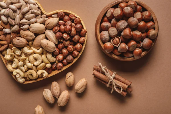 Flat lay with variety of nuts in bowls arranged on brown background — Stock Photo